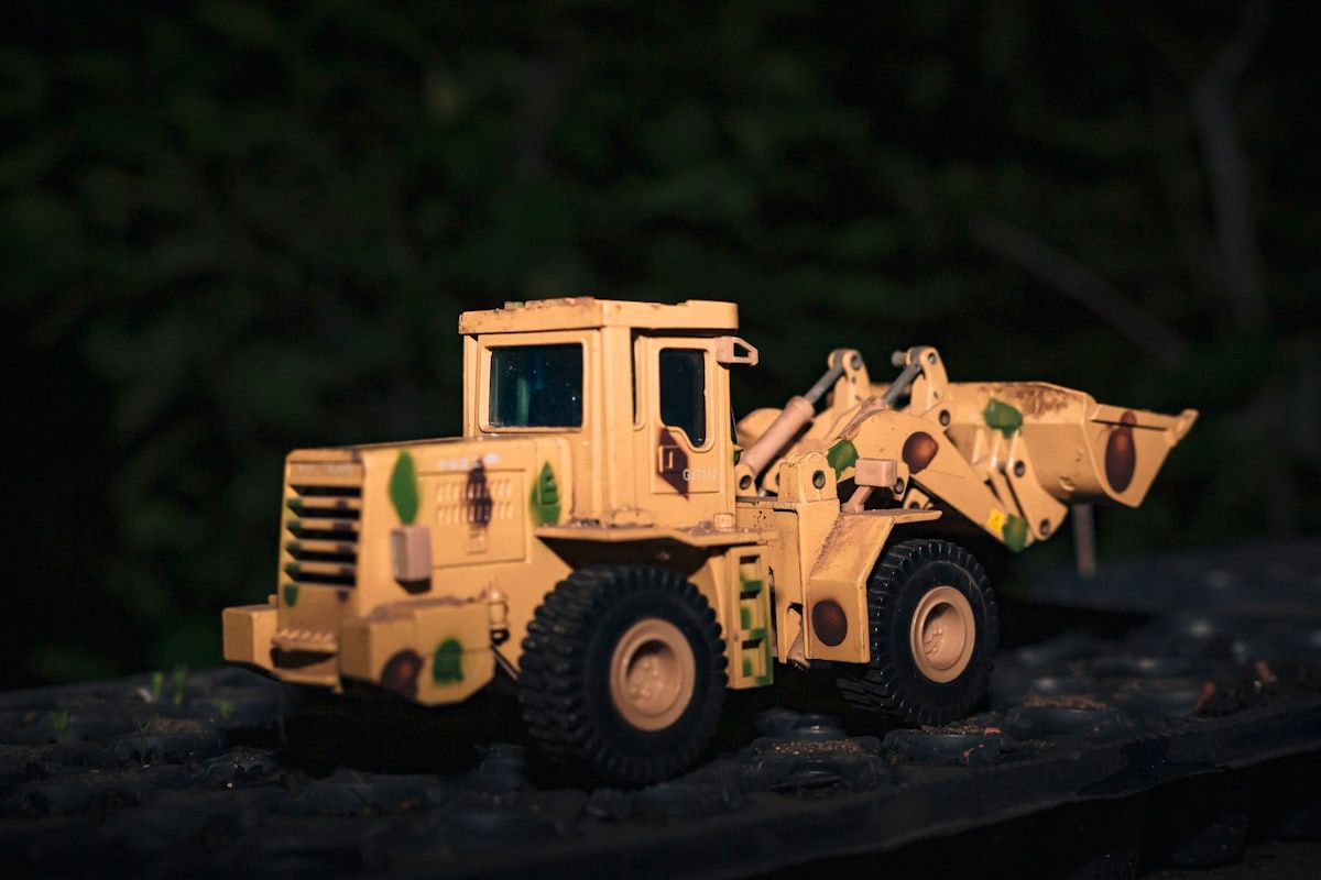 Caminhão de brinquedo amarelo em ambiente natural Caminhão de brinquedo amarelo em meio a árvores verdes, ideal para jogos de construção