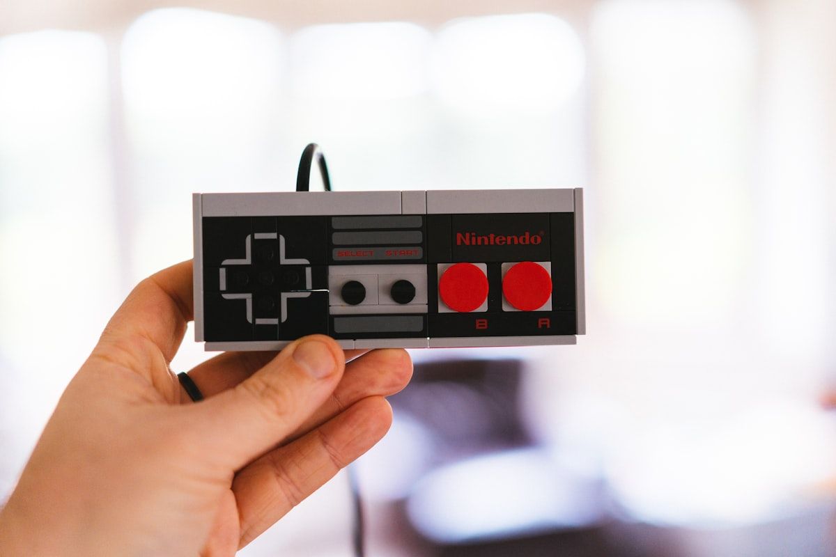 Controle de Nintendo em Legos: Criatividade nos Jogos Controle de Nintendo feito de Legos sendo segurado por uma mão, representando a criatividade em jogos