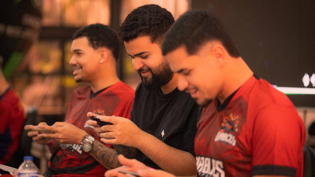 Três amigos se divertindo com jogos mobile em 2026 Três homens jogando jogos mobile juntos em um ambiente descontraído